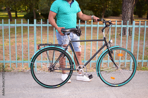 young man holding a bike, green bike, city bike