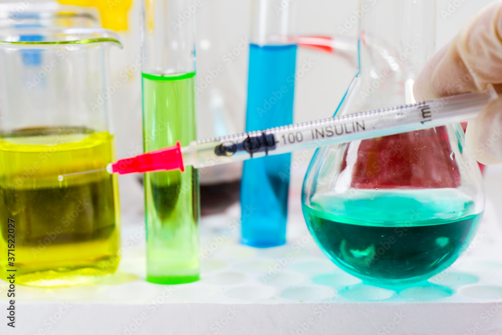 Insulin needle and portion, doctors hand with glove and lab situation.