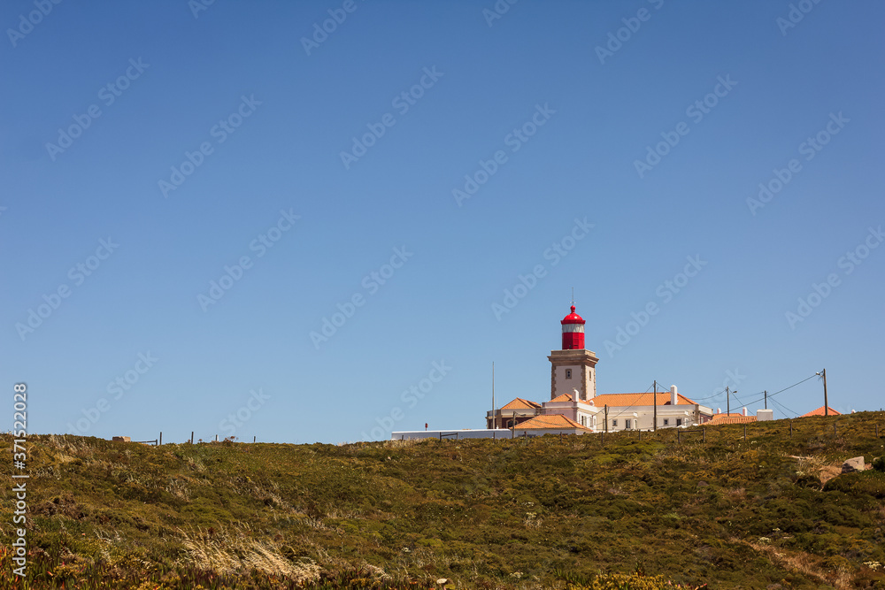 View of Cabo da Roca, Sintra, Portugal, the westernmost point of continental Europe, with its famous lighthouse, surrounded by greenery on a bright summer sunny day
