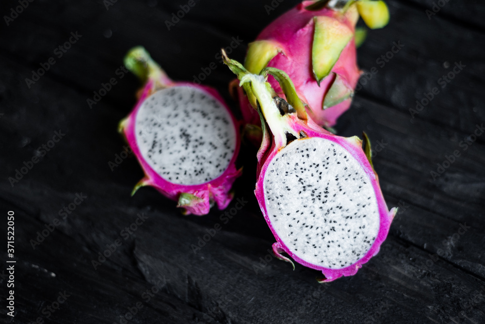 Close up view of exotic dragon fruit sliced isolated on a wooden background. Fresh vegetarians vitamin delicious food. Beautiful picture of summer vacation fruits Close up view of exotic dragon fruit sliced isolated on a wooden background. Fresh vegetarians vitamin delicious food. Beautiful picture of summer vacation fruits