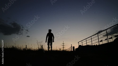 Silhouette of a walking young man, guy at sunset, sunrise, sundown, dusk, twilight, nightfall - 4K  photo