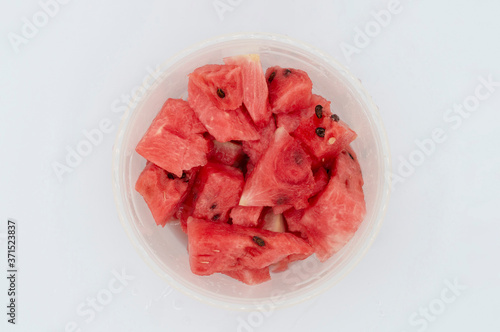 TOP VIEW OF FRESH WATERMELON IN PIECES INSIDE A PLASTIC LUNCH BOX on a white background,