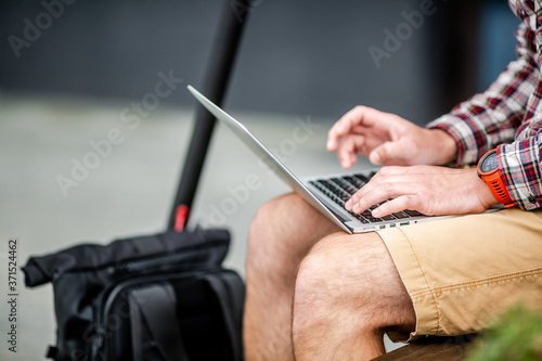 Man is using touchpad and keypad of notebook  close-up of hands. Male hands on keyboard  concept of businessman  working outdoor  online communication. Freelancer Works Outdoors