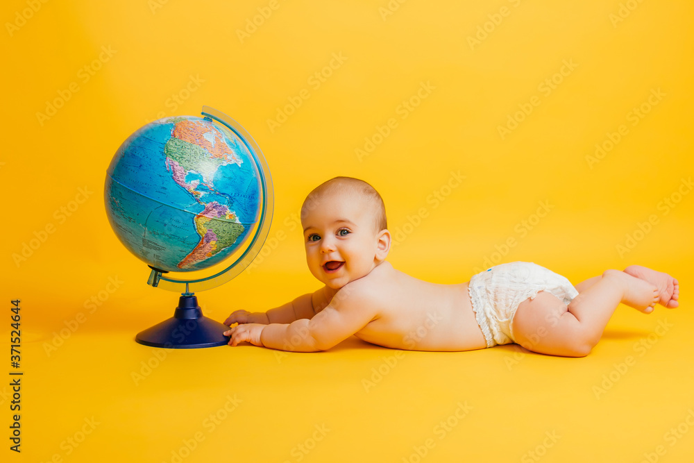 little baby playing with globe on yellow background little baby playing with globe on yellow background
