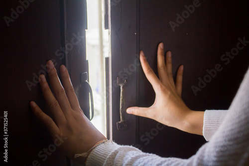 Beautiful hand and sunshine,  Woman hands are pushing the door into outside from wooden home in asia