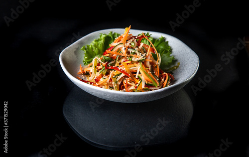 Japanese salad in a white plate on a black background
