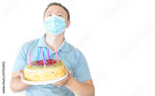 The guy in the mask holds a cake in his hand. Birthday celebration during covid-19 quarantine. White background
