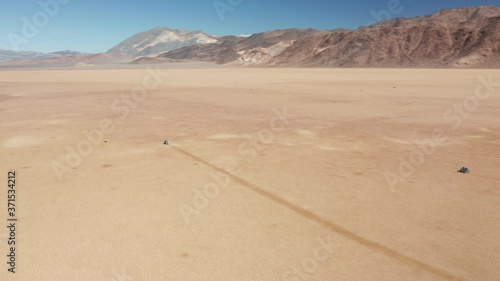 Cinematic 4K aerial around the famous moving rocks in the Death Valley on sunny winter morning. Heavy stones mysteriously moving by the bed of ancient lake bed leaving long race tracks behind, USA