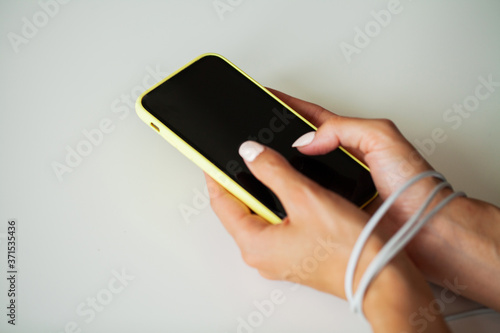 Close up top view of woman hands connected with wire cable to smartphone gadget