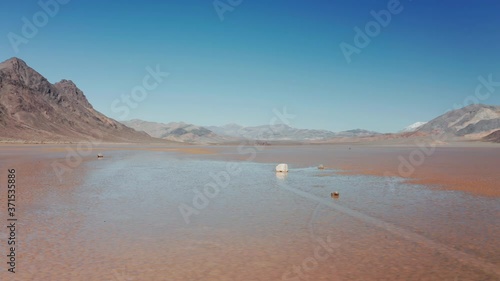 Beautiful cinematic nature of Death valley desert, California, West region, USA. Heavy mystery moving stones on wet cracked surface of Death Valley. Epic flight in untouched pure wilderness landscape