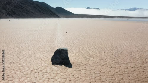 Famous race track playa with moving rocks by the dry cracked surface of Death Valley desert, California, USA. Cinematic 4K aerial around the famous moving rocks in the Death Valley on sunny morning.