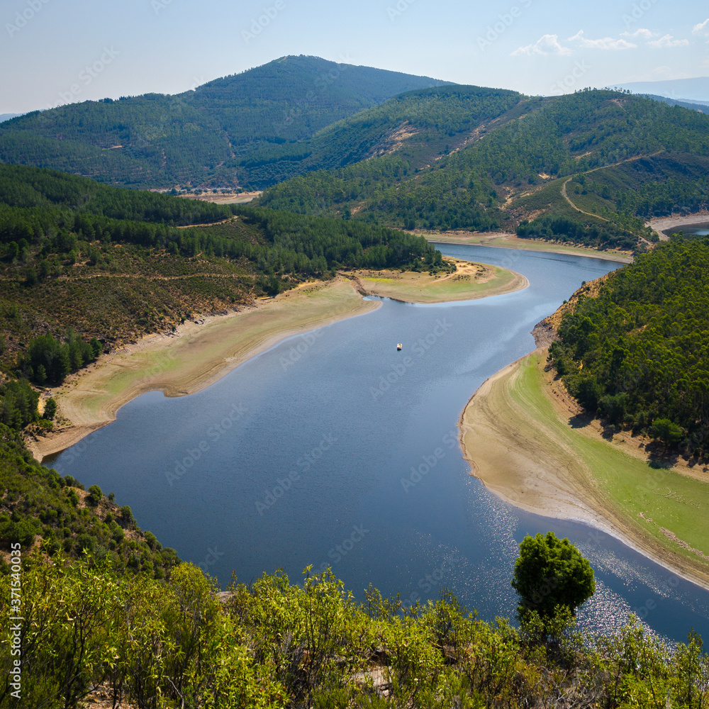 Meander of Melero surrounded by mountains on a day with blue sky, Riomalo de Abajo, Cáceres, Spain Meander of Melero surrounded by mountains on a day with blue sky, Riomalo de Abajo, Cáceres, Spain