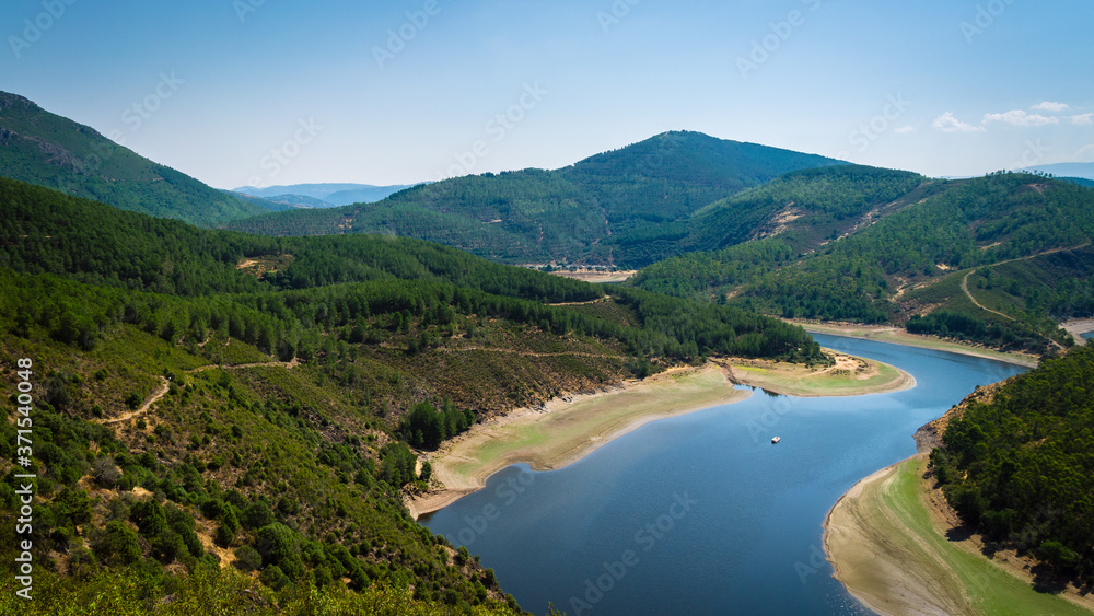 Meander of Melero surrounded by mountains on a day with blue sky, Riomalo de Abajo, Cáceres, Spain Meander of Melero surrounded by mountains on a day with blue sky, Riomalo de Abajo, Cáceres, Spain