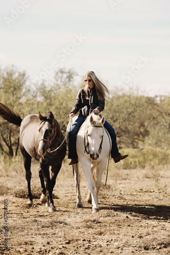 Woman riding bareback on horse shows farm and ranch lifestyle with horses close up ponying through rural Texas field.