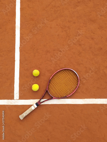 Raqueta y dos pelotas de tenis en una cancha de tenis de polvo de ladrillos photo