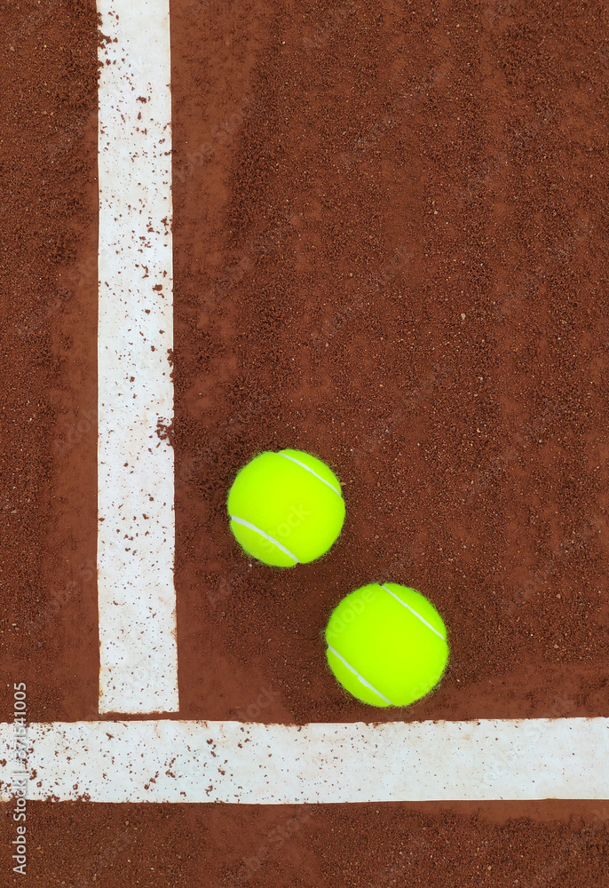 Dos pelotas de tenis en una cancha de tenis de polvo de ladrillo enmacadas entre los flejes de la cancha