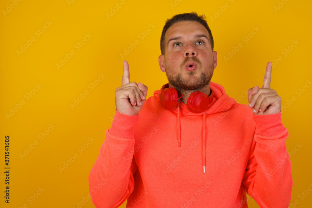 Portrait of handsome elegant man over isolated background being amazed and surprised looking and pointing up with fingers showing something strange. Portrait of handsome elegant man over isolated background being amazed and surprised looking and pointing up with fingers showing something strange.