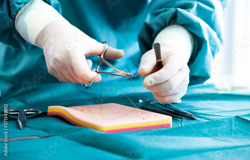 Doctor teaches the technique of suturing and closure on silicone pad. Doctor teaching and suturing practice in basic skills on skin silicone pad. Simple interrupted suture. Vertical mattress suture.