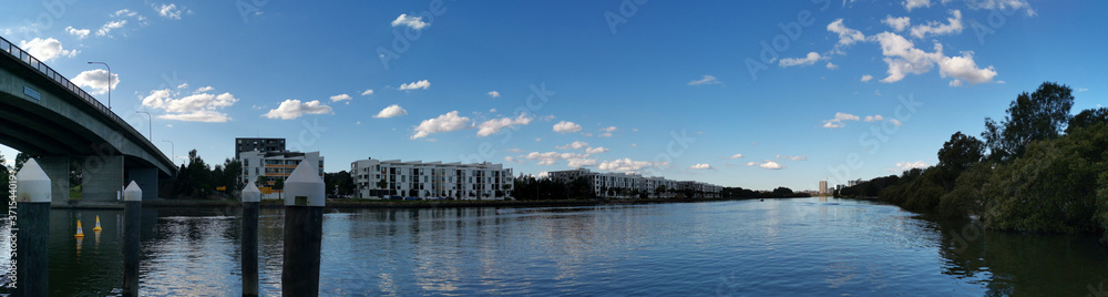 Beautiful panoramic view of a river with reflections of modern apartment buildings, deep blue sky and trees on water, Parramatta river, Wilson Park, Silverwater, Sydney, New South Wales, Australia
