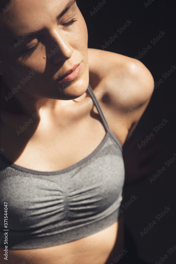 Upper view photo of a sporty lady wearing active wear relaxing in the light of sun after doing fitness Upper view photo of a sporty lady wearing active wear relaxing in the light of sun after doing fitness