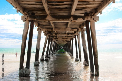One-point perspective shot taken underneath a wooden jetty, or pier, on a beach in South Australia.