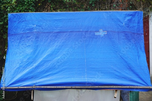 Weathered blue plastic tarp with funky crisscross bandaid patch