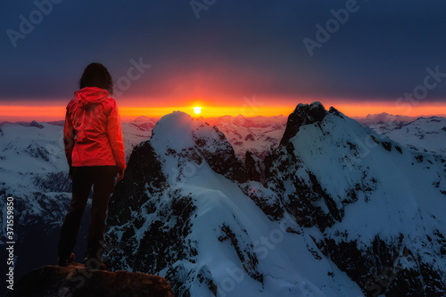 Adventure Dreamscape. Girl on top of a Rocky Mountain Cliff Overlooking a beautiful dramatic landscape during Sunset. Background from British Columbia, Canada.