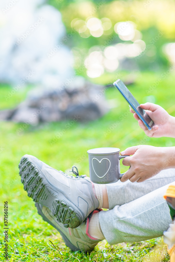 Woman sits inside tend and checks a smartphone for internet contacts or work while sits inside tent. Travel and work concept with an alternative and adventurer lifestyle Woman sits inside tend and checks a smartphone for internet contacts or work while sits inside tent. Travel and work concept with an alternative and adventurer lifestyle
