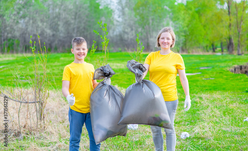 Volunteers carry bags of trash and shows thumbs up gesture. Ecology concept