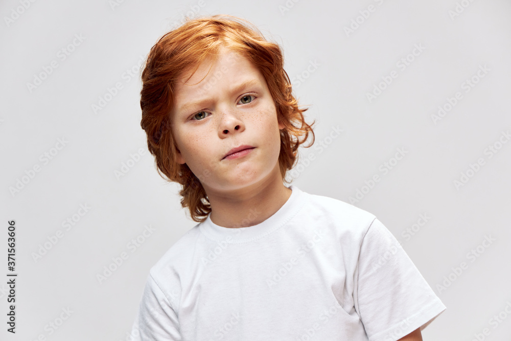 Redhead boy with displeased facial expression White t-shirt cropped view Redhead boy with displeased facial expression White t-shirt cropped view