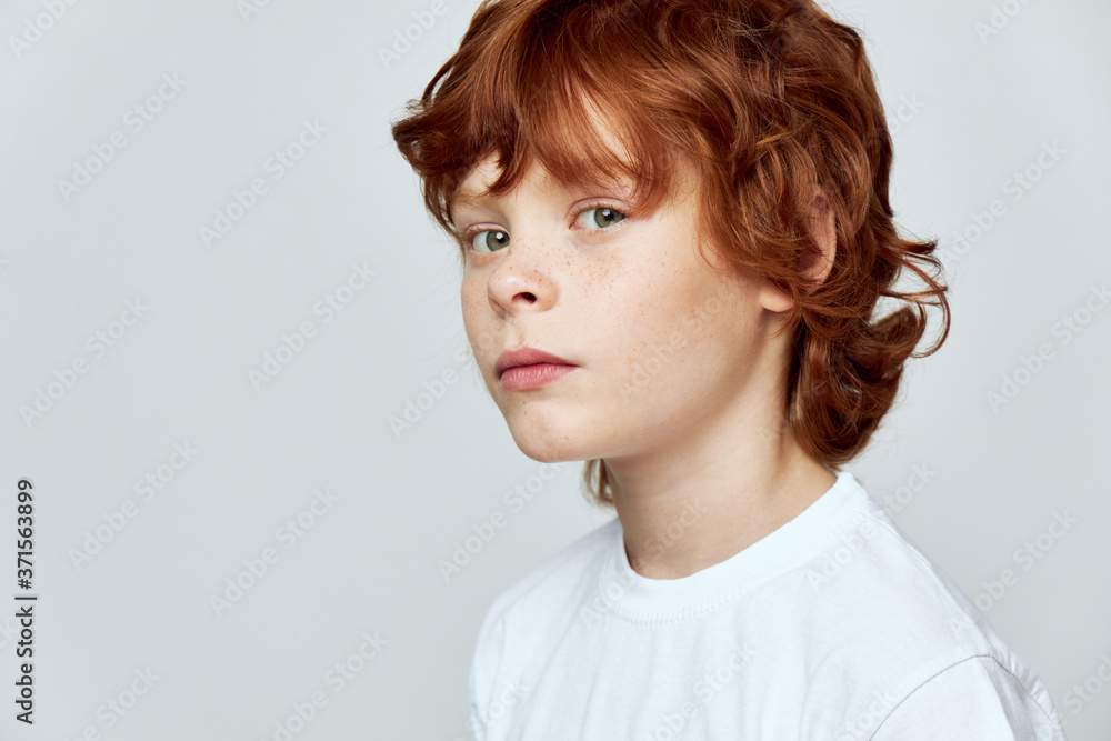 Redheaded child face close-up cropped view of white t-shirt freckles on the face Redheaded child face close-up cropped view of white t-shirt freckles on the face