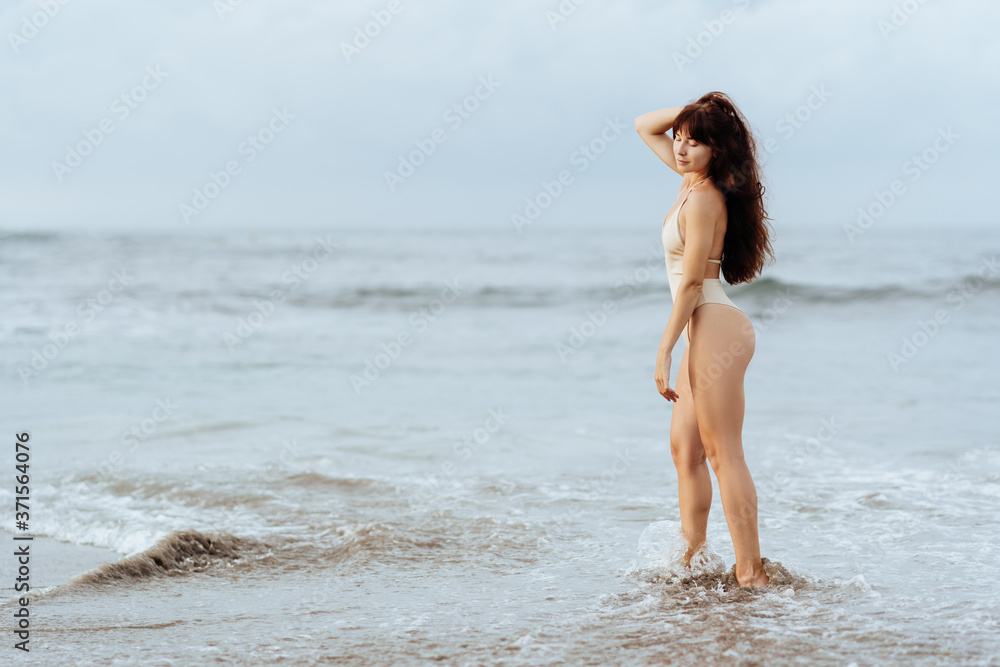Outdoor summer fashion portrait of pretty sexy young woman in bikini posing behind blue ocean Outdoor summer fashion portrait of pretty sexy young woman in bikini posing behind blue ocean