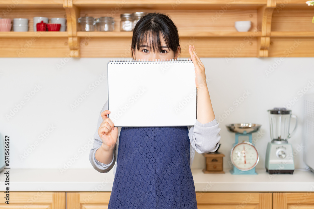 キッチンでスケッチブックを持つ若い女性 キッチンでスケッチブックを持つ若い女性