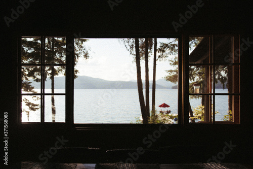 view of lake and mountains and dock sunny through the silhouette of a window