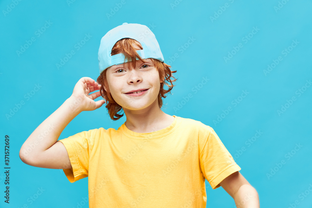 Boy in a blue cap on an isolated background red hair 