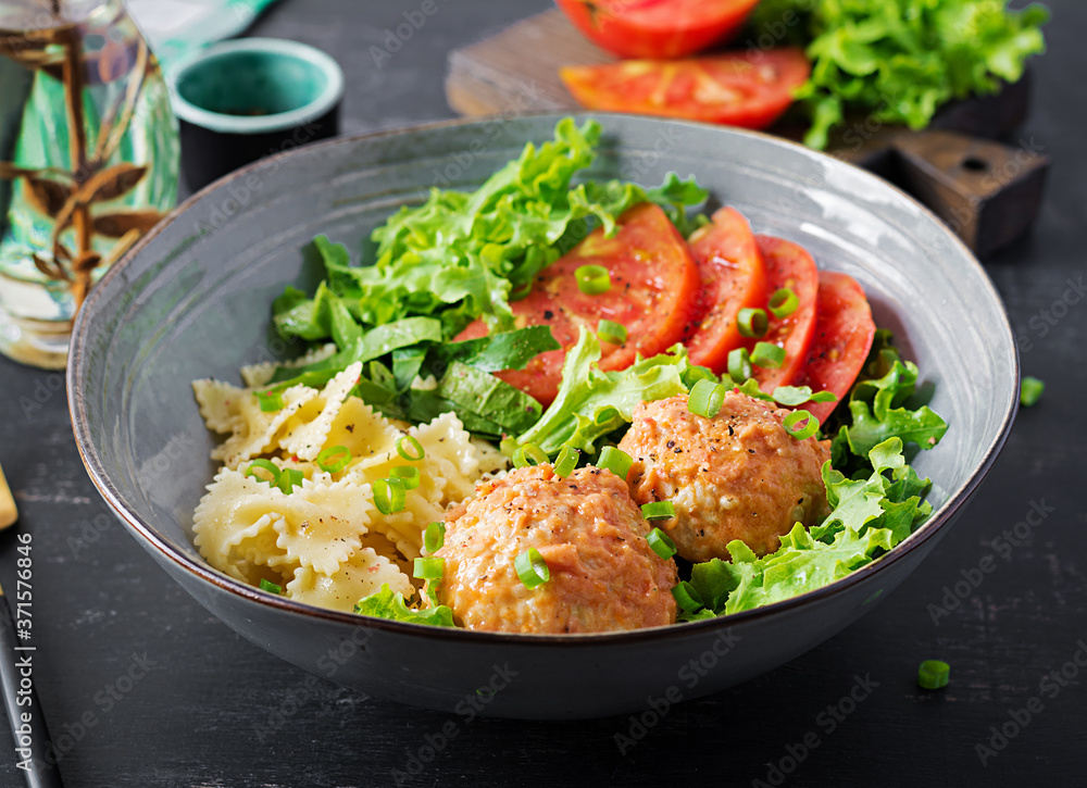 Italian pasta. Farfalle with meatballs and salad on dark background. Dinner. Slow food concept Italian pasta. Farfalle with meatballs and salad on dark background. Dinner. Slow food concept
