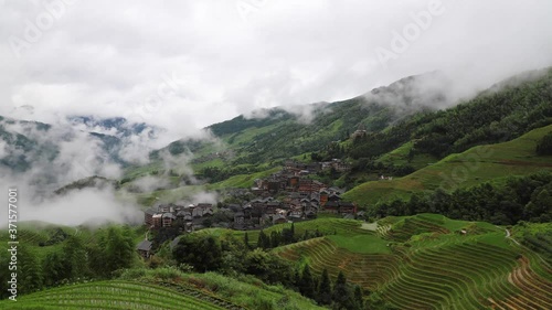 picturesque paddy rice terraces and village houses in Jinkeng, Longji, Guangxi, China in a foggy and cloudy day with occasional rainfall photo