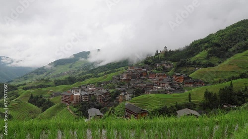 picturesque paddy rice terraces and village houses in Jinkeng, Longji, Guangxi, China in a foggy and cloudy day with occasional rainfall