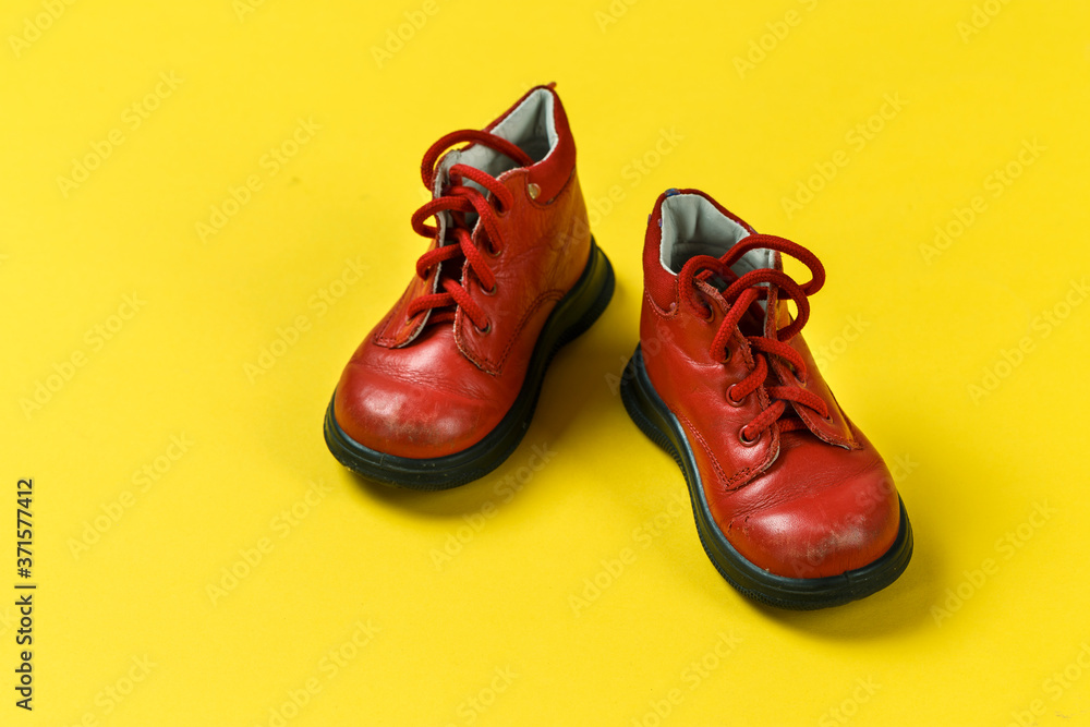 Children's shoes in red on a yellow background.