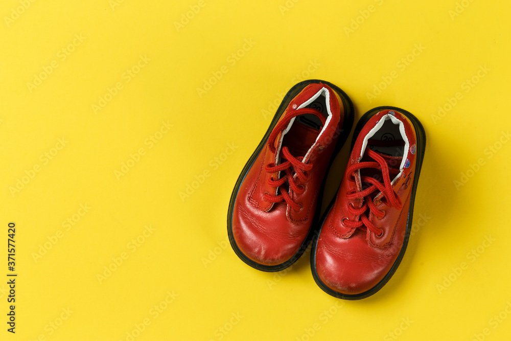 Children's shoes in red on a yellow background. Children's shoes in red on a yellow background.