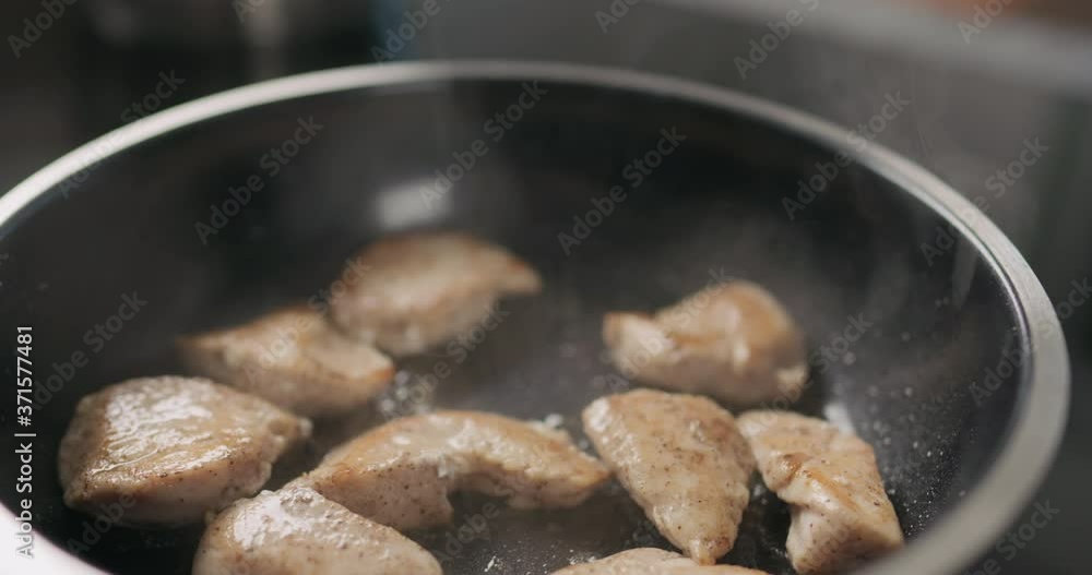 Slow motion handheld shot of chicken fillet slices frying on non-stick pan Slow motion handheld shot of chicken fillet slices frying on non-stick pan