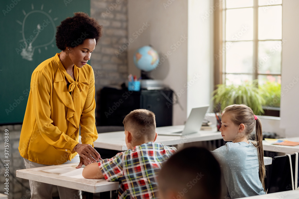 Obraz premium African American teacher assisting her students on on a class at elementary school.