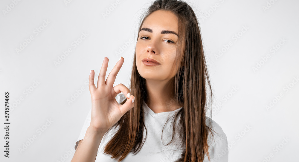Modern stylish girl with long chestnut hair making OK gesture as if saying that everything is fine Modern stylish girl with long chestnut hair making OK gesture as if saying that everything is fine
