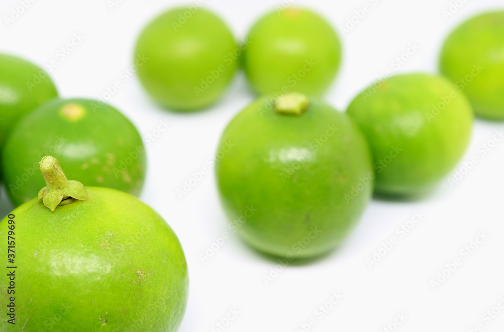 Closeup a vibrant green lime with another scattered on white background Closeup a vibrant green lime with another scattered on white background