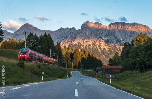 Rural mountain road near Mittenwald, Bavaria, Germany with Karwendel mountains on background at sunset. Idyllic mountain scene. 