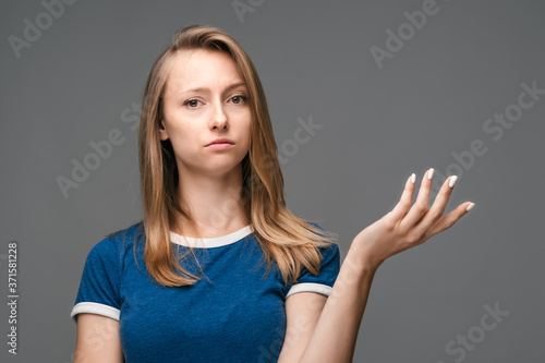 Studio shot of frustrated female gesturing with raised palm, frowning, being displeased and confused with dumb question