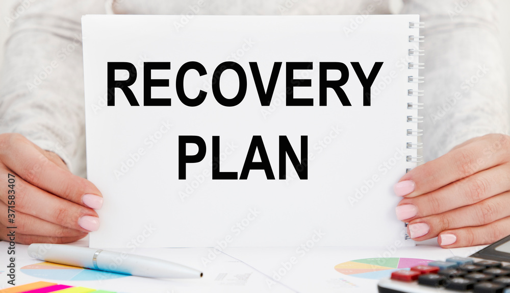 Business girl removes a business card in her pocket with the inscription RECOVERY PLAN. Business girl removes a business card in her pocket with the inscription RECOVERY PLAN.