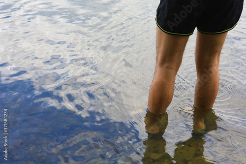 Male feet in the water on the river with copy space for an inscription or text photo