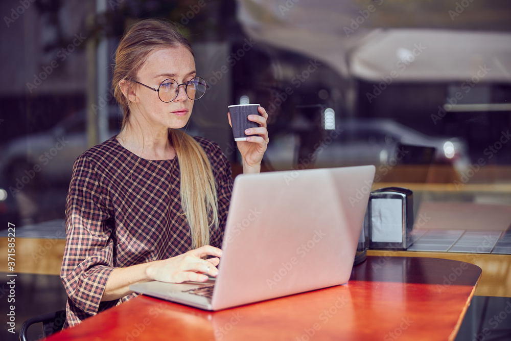 Pretty girl with freckles in glasses working on the laptop Pretty girl with freckles in glasses working on the laptop