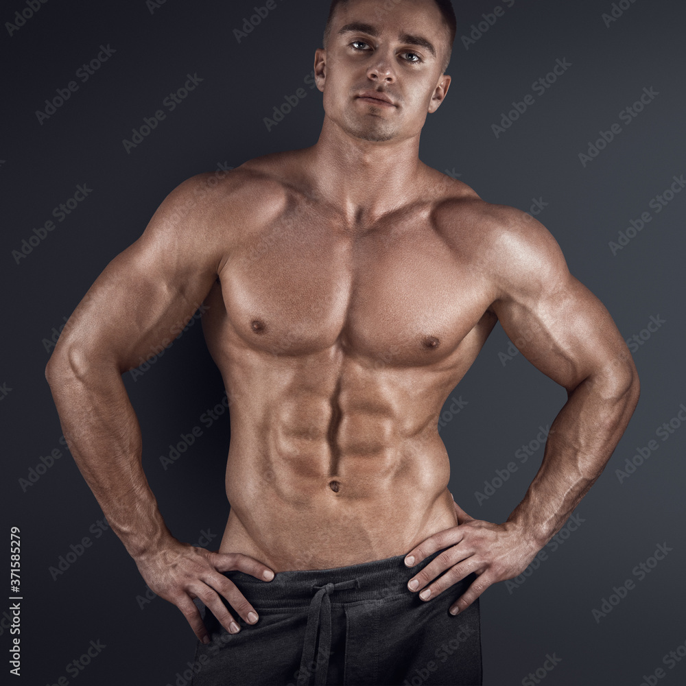 Fototapeta premium Sexy shirtless male model posing against dark background